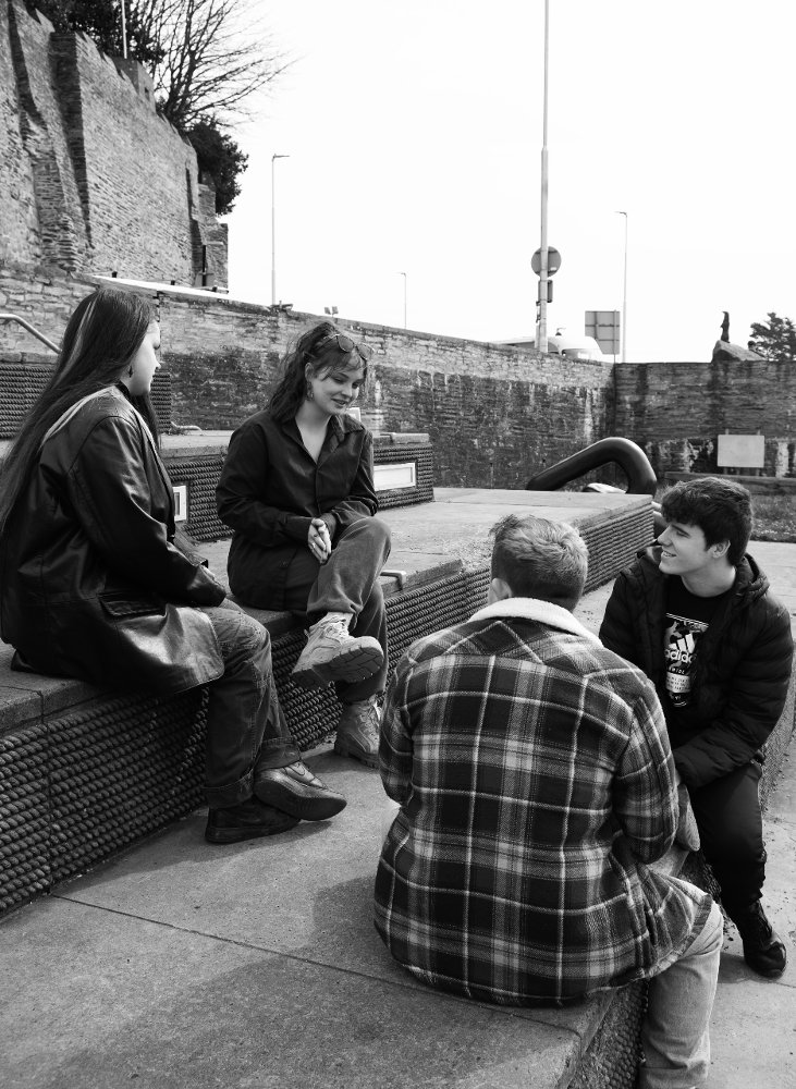 Dyfodol Ni Group of 4 people sat on large steps Black & White